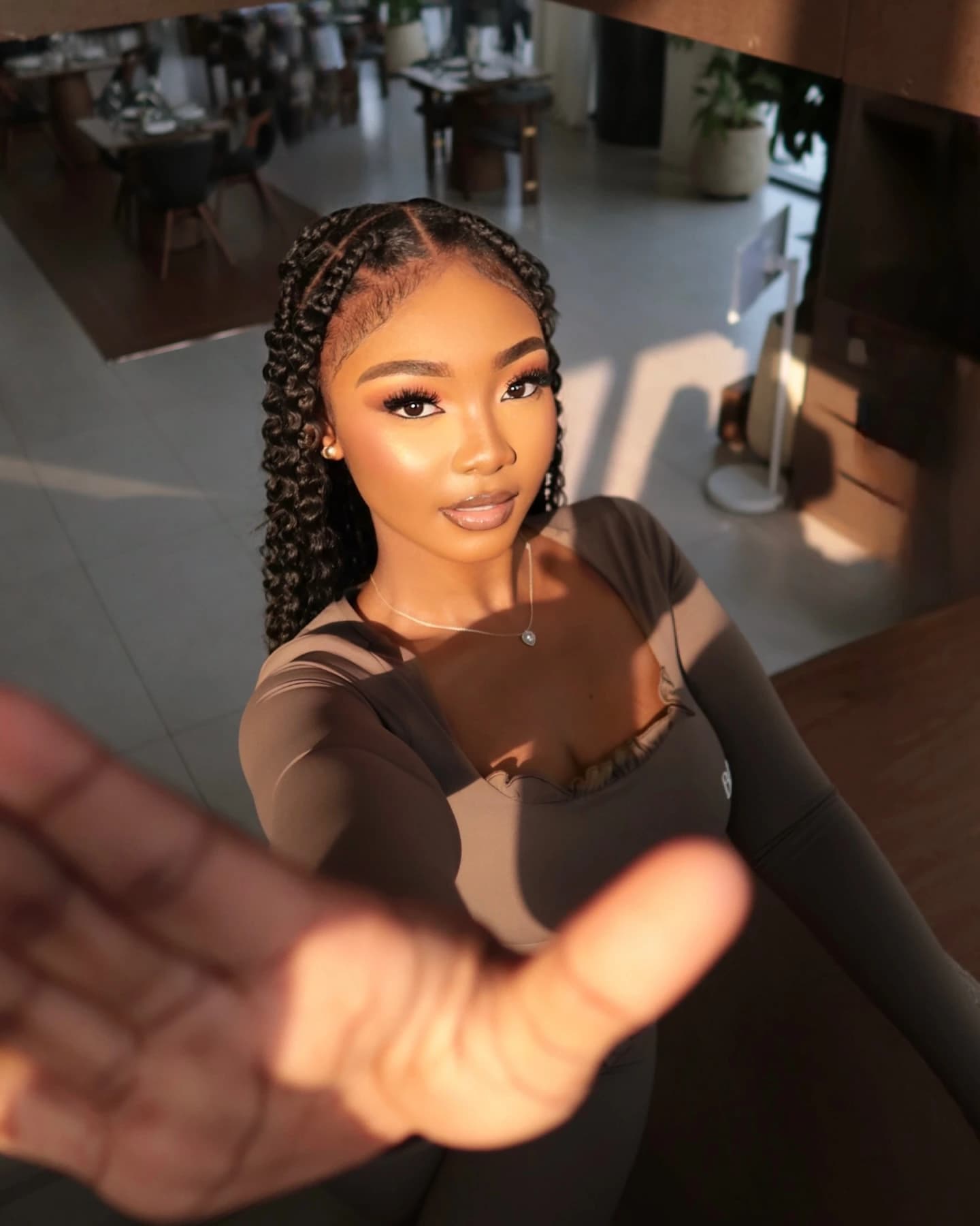 Close portrait in warm sunlight with a hand reaching toward the lens.
